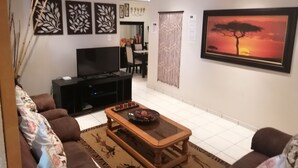 Un salón con sofá, mesa de centro, televisor y obras de arte.