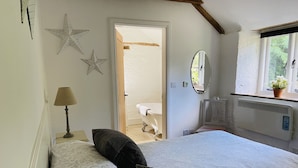 A bedroom with a bed, a bedside lamp, a star decoration, a mirror, and a radiator. - Beautiful Barn Conversion With Wood-burning Stove (Yeovil)