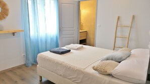 Un dormitorio con una cama, una escalera de madera, una cortina azul y una puerta que da a un baño.