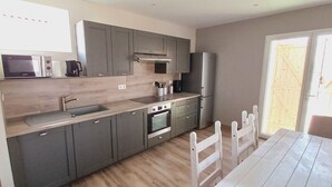 Una cocina moderna con gabinetes grises, horno empotrado y refrigerador de acero inoxidable.