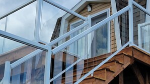 Una escalera de madera con barandillas de vidrio que conduce a un ventanal del segundo piso.