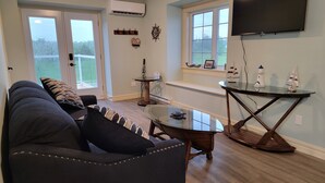 Una sala de estar con un sofá, una mesa de centro y un televisor montado en la pared.