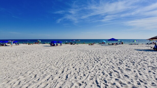 A sandy beach with umbrellas and people.