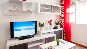 Ein modernes Wohnzimmer mit Flachbildfernseher, weißen Regalen und einem roten Vorhang.