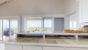 A kitchen with a large window, a view of the sea, and a white countertop. - ☀️🌴Breezy Bird by IRE Vacations - Cozy 2 bedroom Villa with Private Pool (Oyster Pond)
