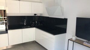 Ett modernt kök med vita skåp, en svart bänkskiva och en inbyggd ugn.
