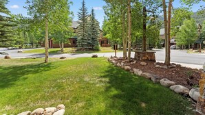 A residential area with a well-maintained lawn, trees, and a stone border. - Condo in River Run Village Only Walking Distance to Surrounding Lifts! (Keystone)