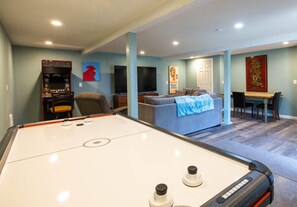 Quarto com mesa de bilhar, sofá, televisão e mesa de jantar.