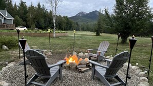 An outdoor seating area with Adirondack chairs around a fire pit, surrounded by rocks and gravel. - Snowmobile & ATV right on our property to trails, Ride the wilds, corridor 5. (Stark)