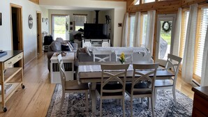 A cozy cabin interior with a dining area, kitchen, and large windows. - Snowmobile & ATV right on our property to trails, Ride the wilds, corridor 5. (Stark)