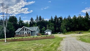 A two-story house with a deck, a garage, and a gravel driveway. - Snowmobile & ATV right on our property to trails, Ride the wilds, corridor 5. (Stark)