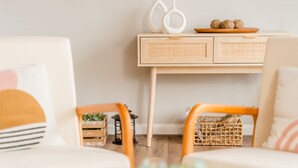 A cozy living room with a light wooden desk, two white vases, and a wooden tray with decorative balls. There are wicker baskets and a small plant on the floor. - Hot Tub Mountain View Dog Friendly Modern Chalet (Linden)