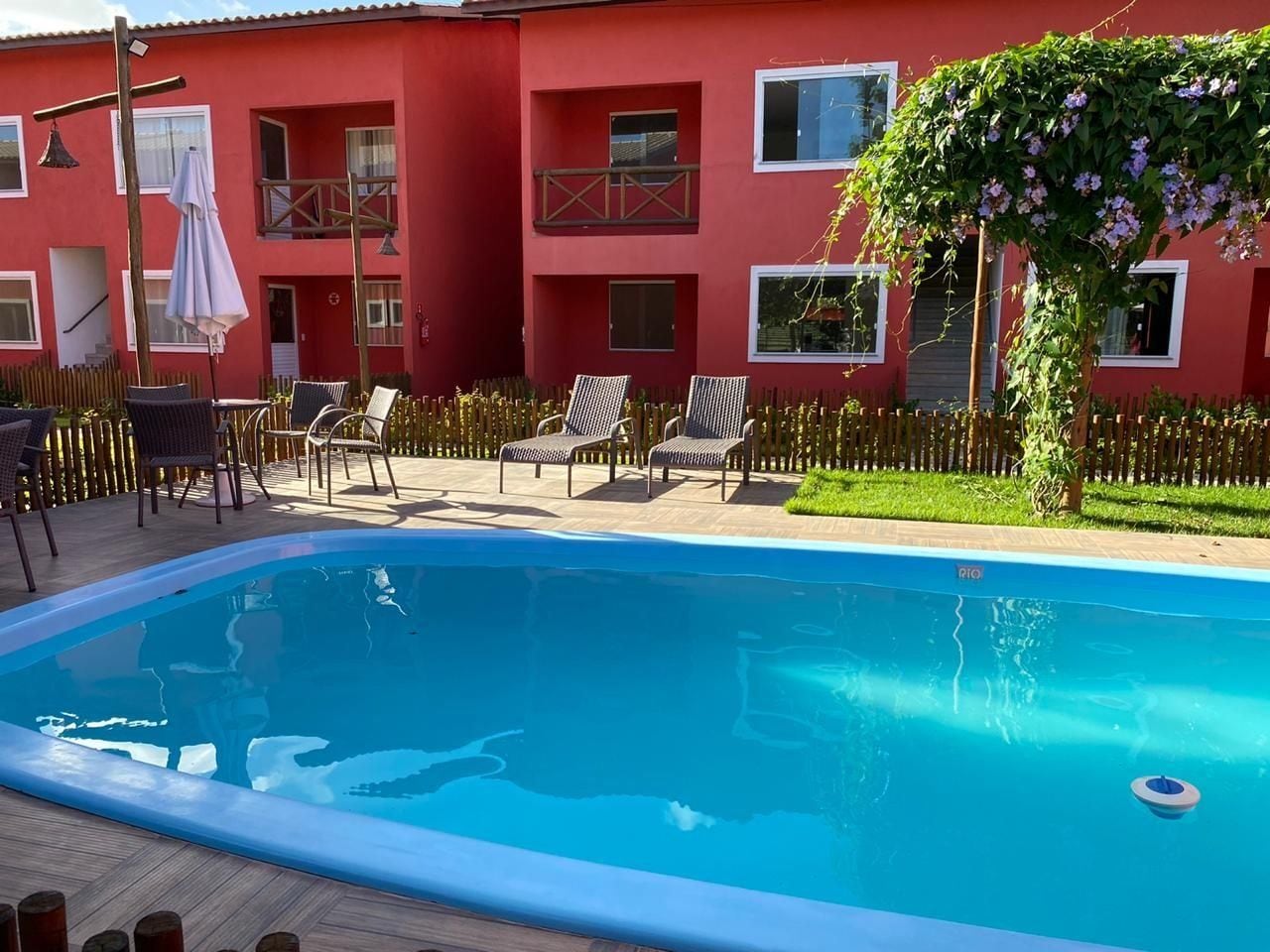 A swimming pool with lounge chairs and a red building in the background.