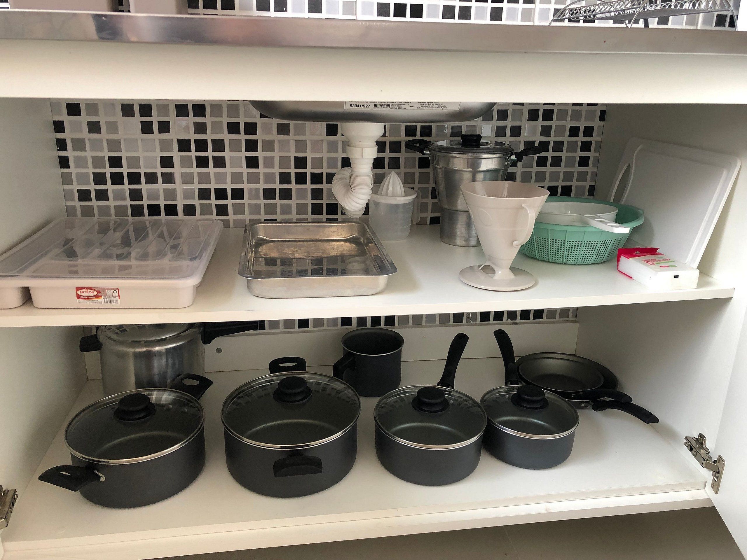 Una cocina con gabinetes blancos, encimera blanca y salpicadero de azulejos.