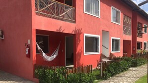 Un edificio rojo con múltiples ventanas, un extintor y una hamaca.