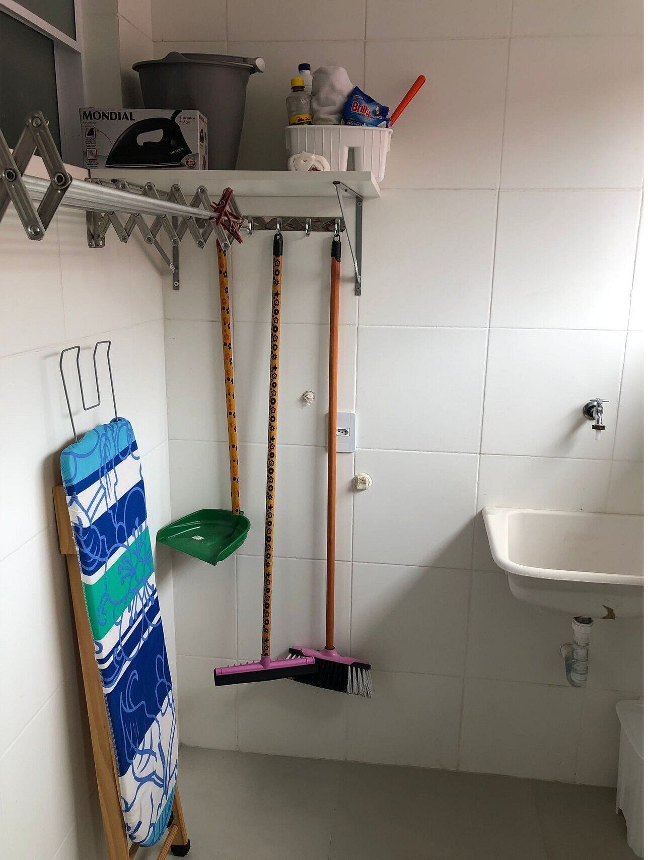 Un baño con lavamanos, espejo y repisas con productos de limpieza.