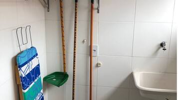 Un baño con lavamanos, espejo y repisas con productos de limpieza.