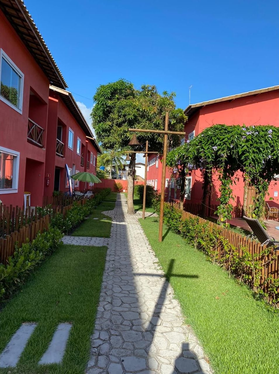 Un camino que lleva a un edificio de fachada roja, rodeado de césped cuidado y una valla de madera.
