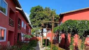 Un camino que lleva a un edificio de fachada roja, rodeado de césped cuidado y una valla de madera.