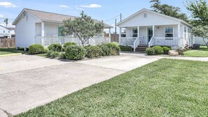 A two-story house with a front porch, a small front yard, and a clear sky.