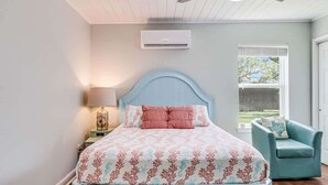 A bedroom with a bed, a nightstand, a lamp, a ceiling fan, and a window.