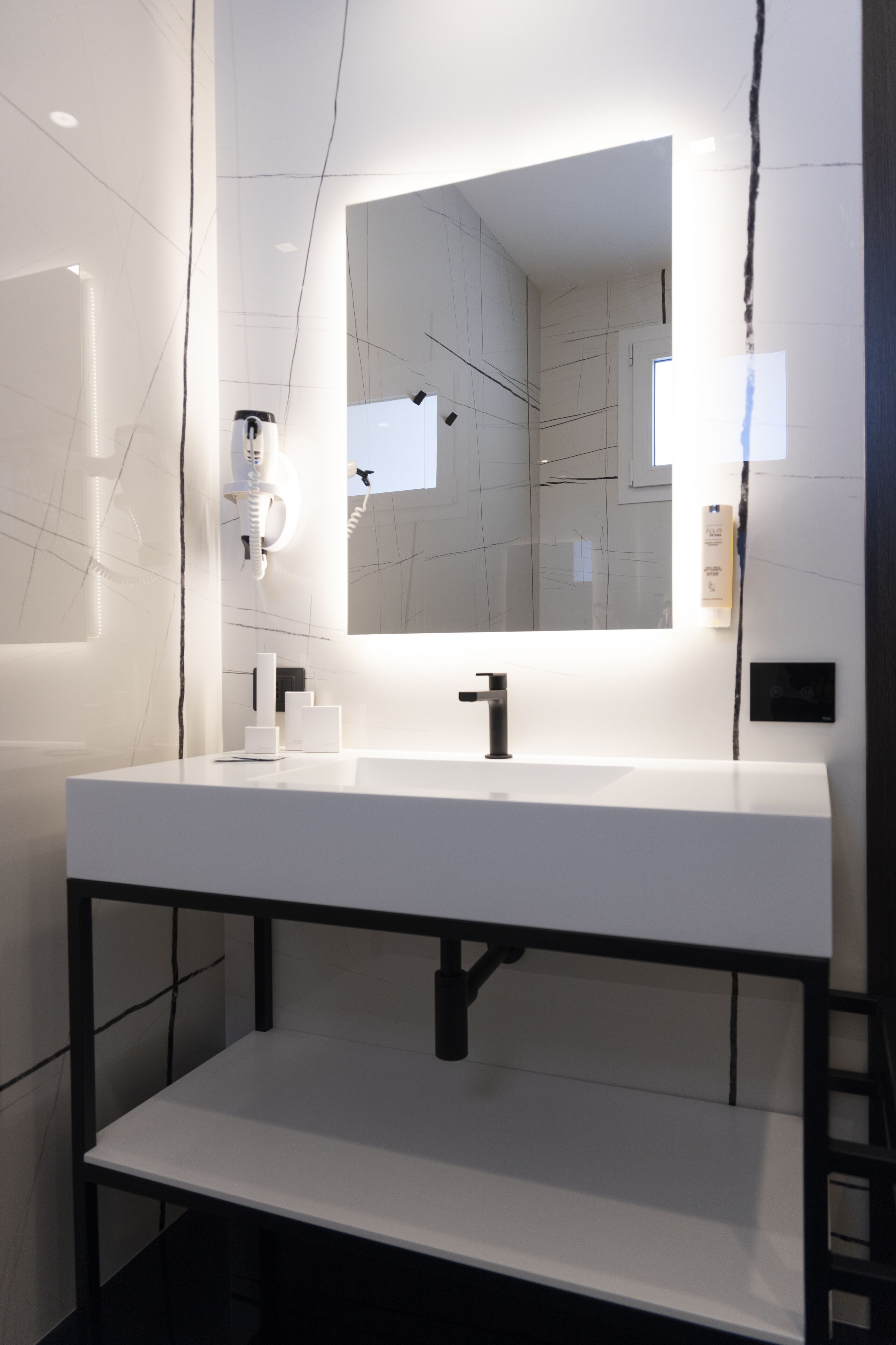 A modern bathroom with a white sink, black faucet, and a large mirror.