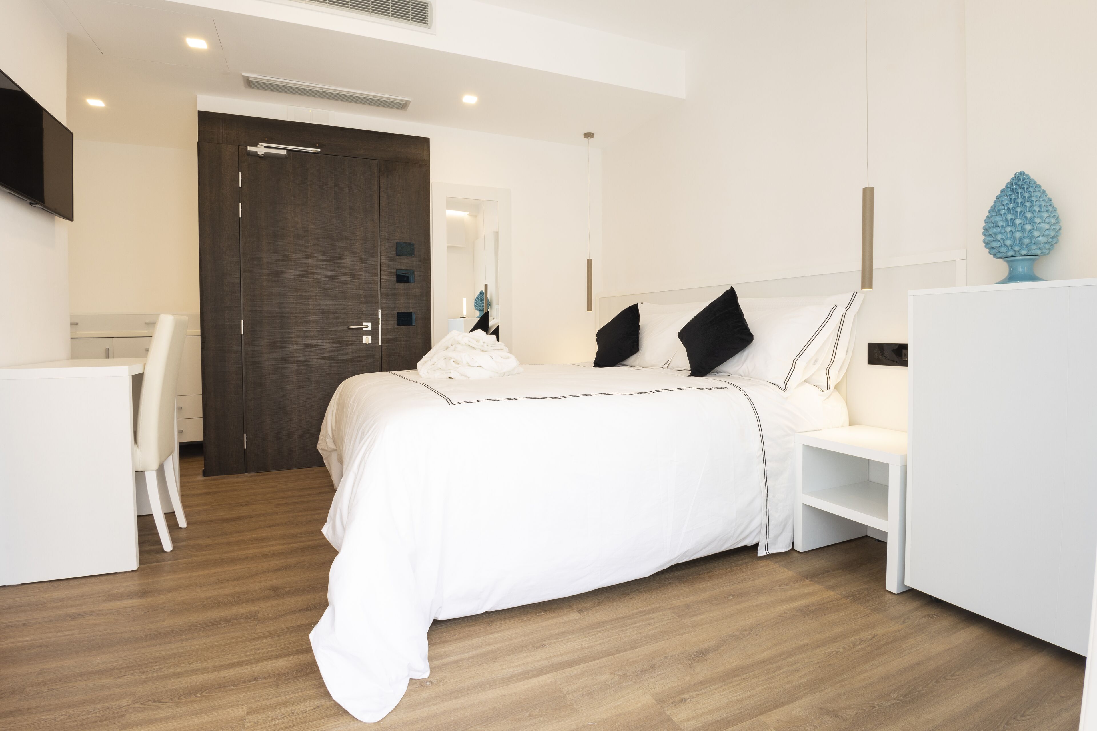 A modern bedroom with a bed, bedside tables, a desk, and a wardrobe.