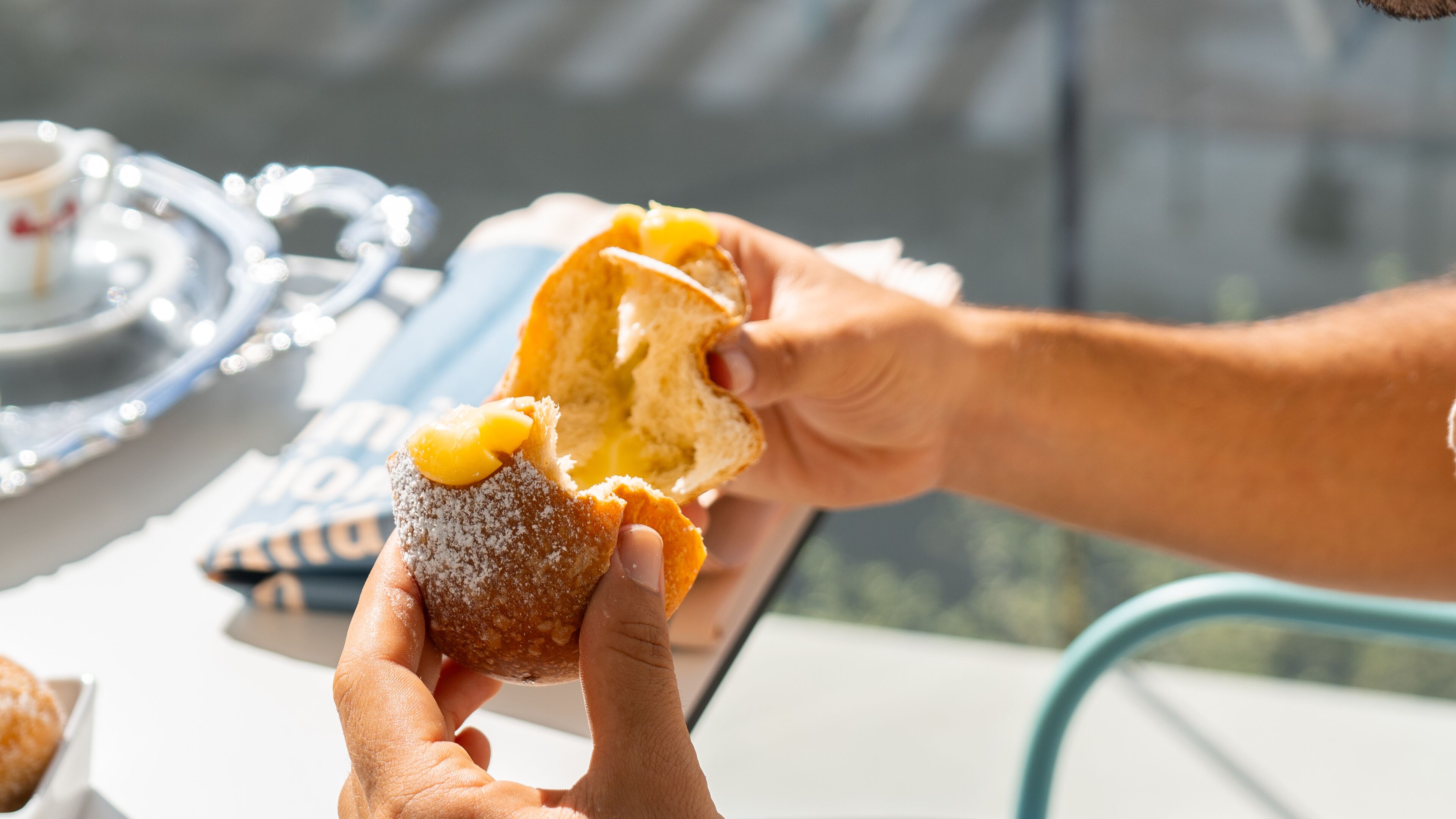 Une personne tenant un beignet enrobé de sucre glace dans lequel on a croqué.