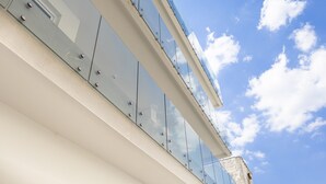 Un edificio moderno con barandillas de vidrio y un cielo azul despejado.