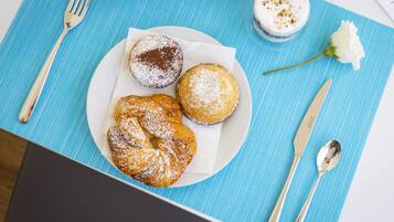 A plate with four pastries on a blue placemat, accompanied by a fork, knife, and spoon.