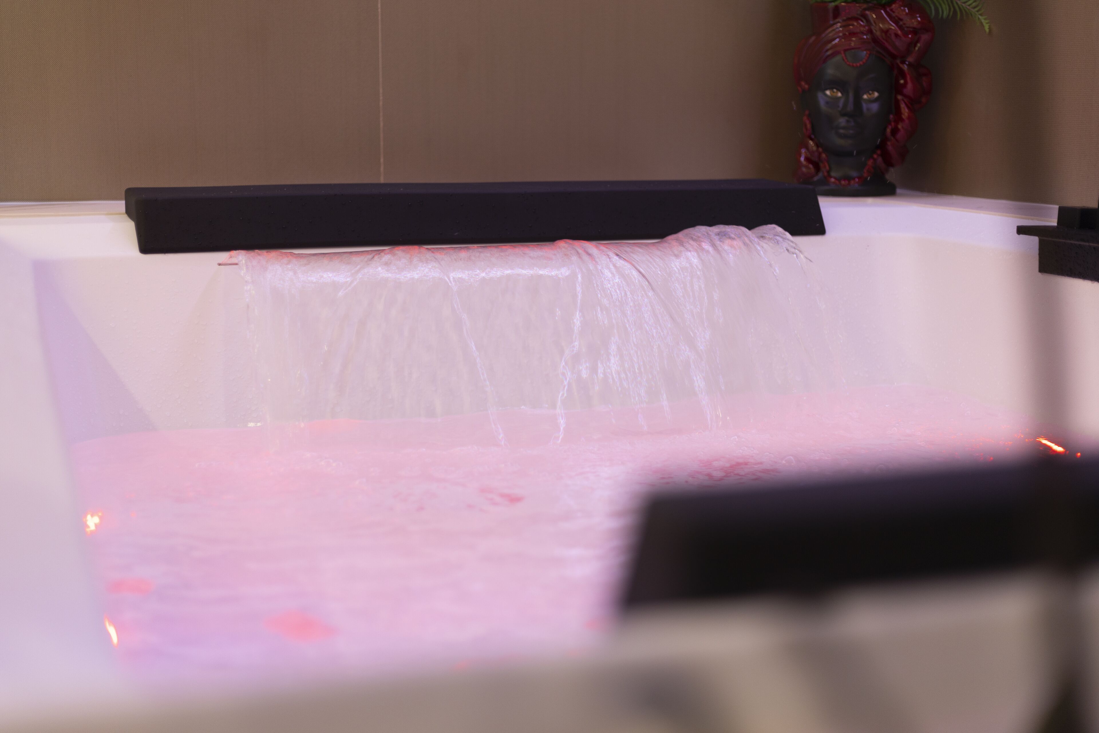 A bathtub with a black edge and a decorative item in the background.