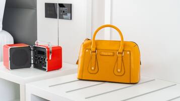 A yellow handbag on a white table with a red and black radio beside it.