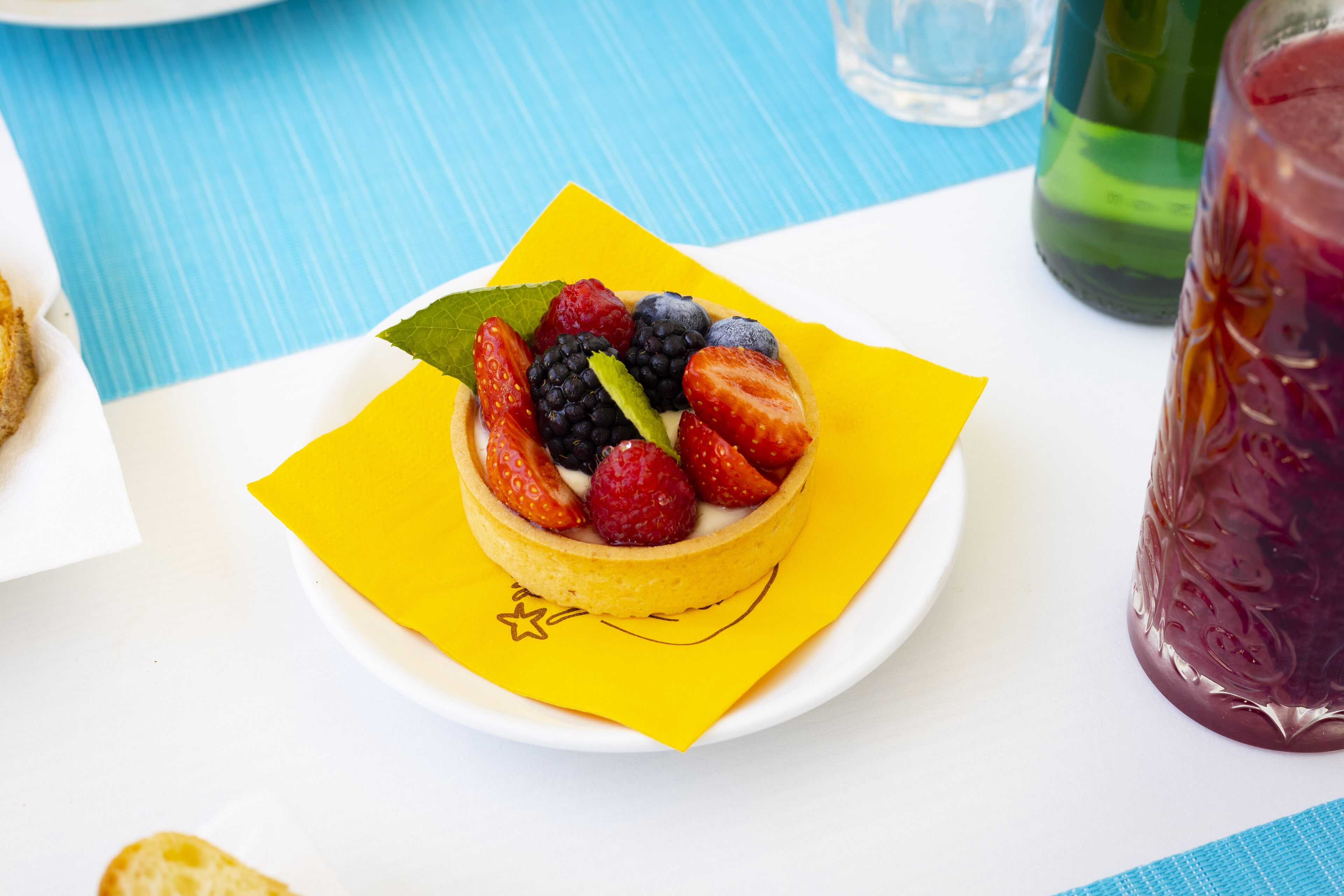 A dessert on a white plate with a yellow napkin, surrounded by a blue striped tablecloth.