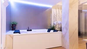 Un baño moderno con una bañera grande, dos lavamanos y plantas decorativas.