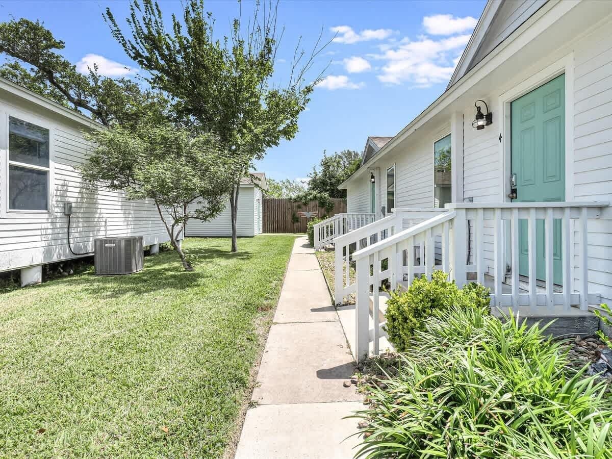 A residential area with a pathway leading to a house with a white exterior and green shutters.