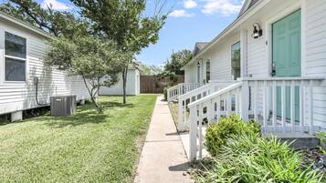A residential area with a pathway leading to a house with a white exterior and green shutters.