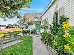 A residential house with a front porch, a green door, and a driveway leading to a parked vehicle.