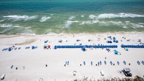 A beach with rows of blue umbrellas and beach chairs, a sandy shore, and the ocean. - 2 King bedrooms in this 15th floor condo at the Splash w/Beach Chairs! (Panama City Beach)