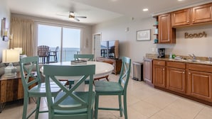 A kitchen with wooden cabinets, a dining area with a round table and chairs, and a view of the ocean through large windows. - 2 King bedrooms in this 15th floor condo at the Splash w/Beach Chairs! (Panama City Beach)
