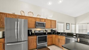 A modern kitchen with stainless steel appliances, wooden cabinets, and a black countertop. - Lovely Villa with a pool/ Ideal for long stays / Message for discounts. (Davenport)