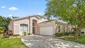 A two-story house with a garage, a driveway, and a well-maintained lawn. - Lovely Villa with a pool/ Ideal for long stays / Message for discounts. (Davenport)