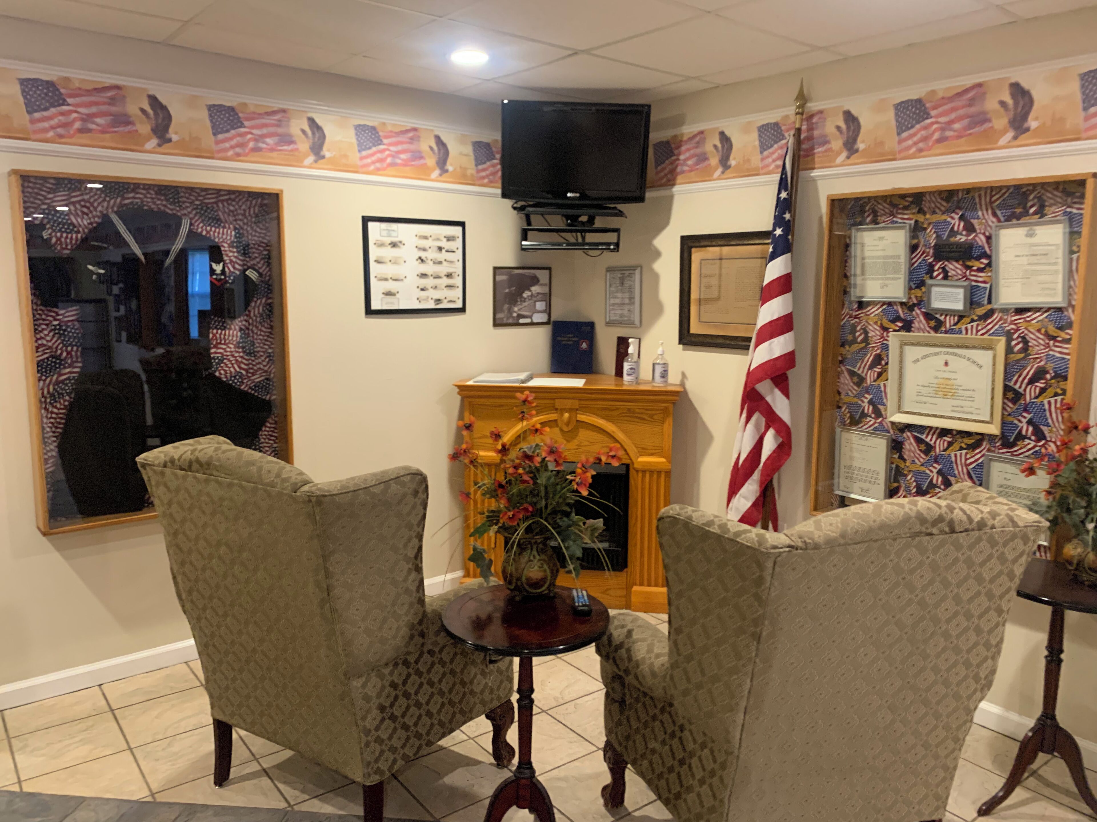 A room with two armchairs, a small table, a fireplace, and American flag decorations.
