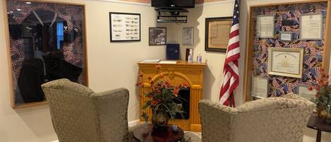 A room with two armchairs, a small table, a fireplace, and American flag decorations.