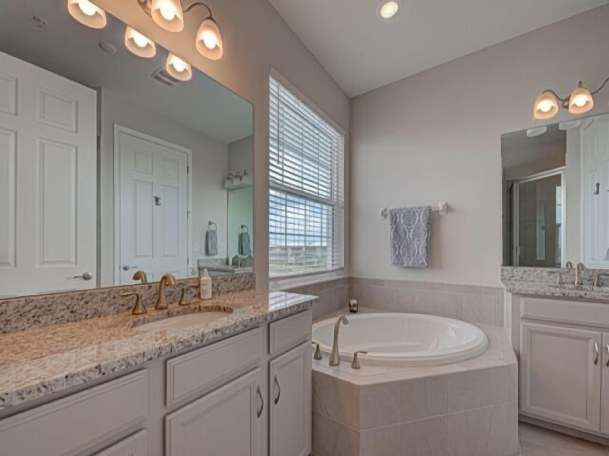 A modern bathroom with a large bathtub, double sinks, and a vanity with a mirror.