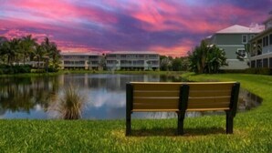 A bench by a lake with a building in the background. - Tropical Paradise - Resort Style Pool - Private Elevator (Placida)