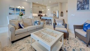 A modern living room with a sofa, armchairs, a coffee table, and a kitchen in the background. - Tropical Paradise - Resort Style Pool - Private Elevator (Placida)