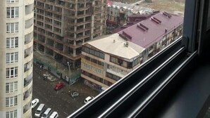 Un immeuble de grande hauteur, avec de nombreux étages, dont certains dotés de balcons, et une grue de construction visible à l’arrière-plan.