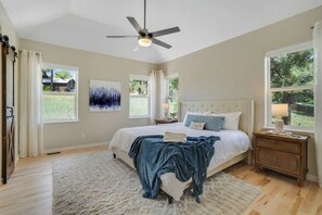 A bedroom with a bed, a ceiling fan, a nightstand, a window, and a painting on the wall. - Large Home, Hot Tub, Close to Lakes and Shopping (Pagosa Springs)