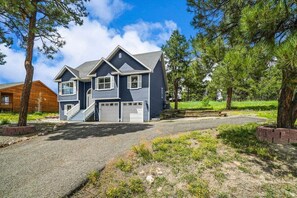 A two-story house with a front garage, a staircase leading to the entrance, and a driveway. - Large Home, Hot Tub, Close to Lakes and Shopping (Pagosa Springs)