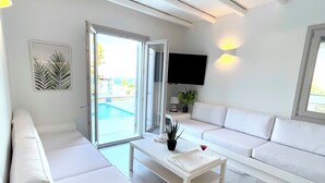 A modern living room with a white sofa, a coffee table, and a TV mounted on the wall.